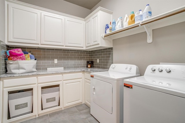 clothes washing area featuring light tile patterned floors, cabinet space, and washing machine and dryer