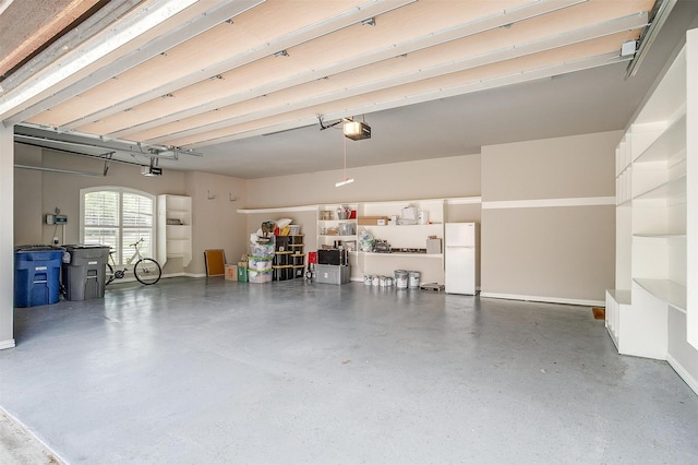 garage featuring freestanding refrigerator, baseboards, and a garage door opener