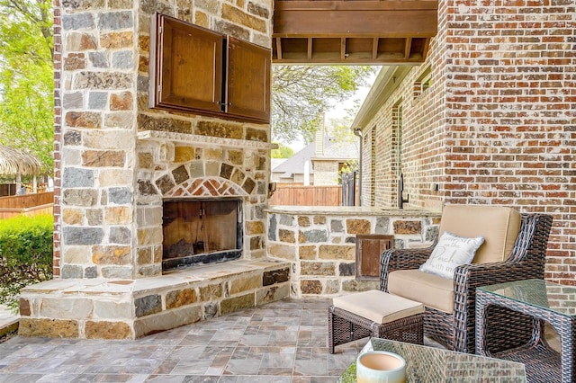 view of patio with an outdoor stone fireplace and fence