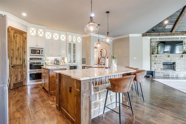 kitchen featuring glass insert cabinets, stainless steel appliances, a spacious island, and tasteful backsplash