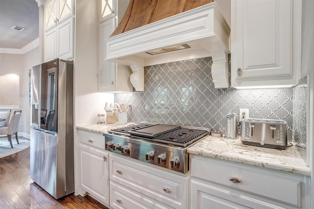kitchen featuring premium range hood, stainless steel appliances, white cabinetry, and ornamental molding