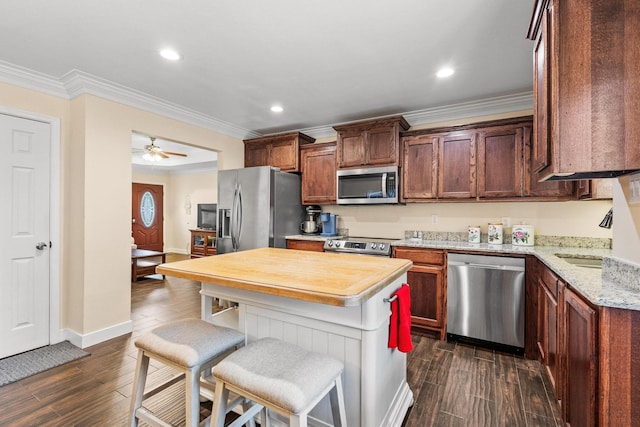 1321 S Montgomery St, Sherman, TX 75090 - kitchen featuring appliances with stainless steel finishes, a sink, crown molding, a kitchen bar, and dark wood finished floors