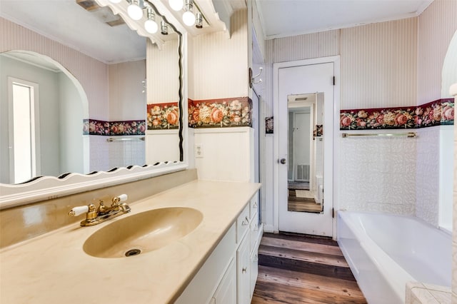 302 Comanche Dr, Gainesville, TX 76240 - full bathroom featuring wood finished floors, a bathtub, crown molding, and wallpapered walls