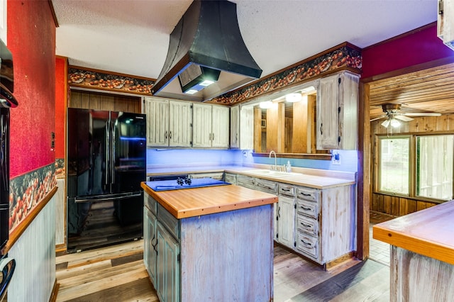 302 Comanche Dr, Gainesville, TX 76240 - kitchen featuring butcher block counters, freestanding refrigerator, extractor fan, a sink, and light wood-type flooring