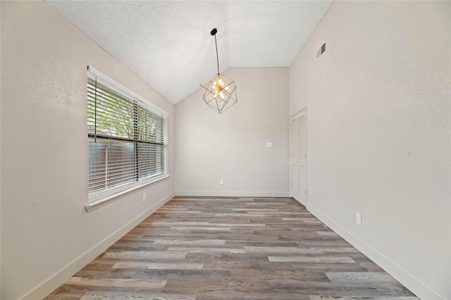 1581 Glenmore Dr, Lewisville, TX 75077 - unfurnished dining area featuring visible vents, baseboards, an inviting chandelier, wood finished floors, and lofted ceiling