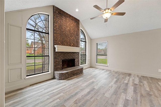 1581 Glenmore Dr, Lewisville, TX 75077 - unfurnished living room featuring a textured ceiling, a ceiling fan, a brick fireplace, high vaulted ceiling, and wood finished floors