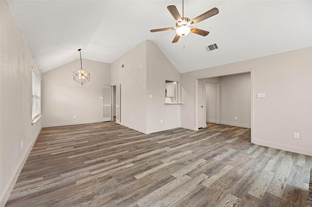 1581 Glenmore Dr, Lewisville, TX 75077 - unfurnished living room with ceiling fan with notable chandelier, wood finished floors, lofted ceiling, and visible vents
