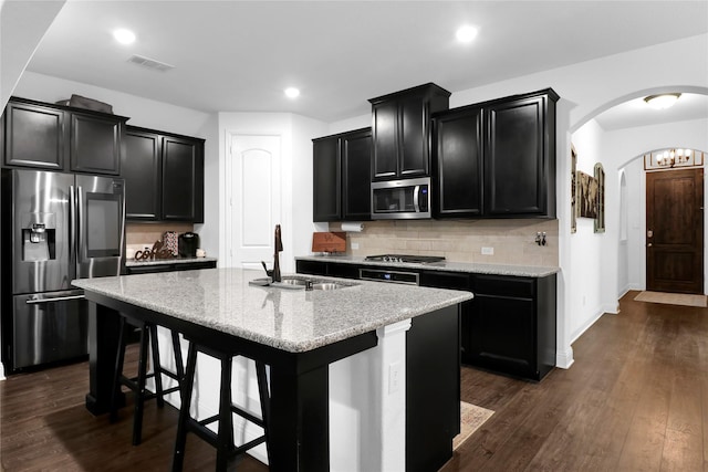 14649 Martin Creek Cv, Fort Worth, TX 76262 - kitchen with stainless steel appliances, dark cabinetry, a sink, arched walkways, and a kitchen island with sink