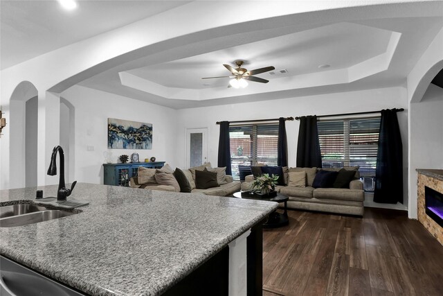 14649 Martin Creek Cv, Fort Worth, TX 76262 - kitchen with a tray ceiling, arched walkways, a sink, dark wood-style flooring, and a ceiling fan