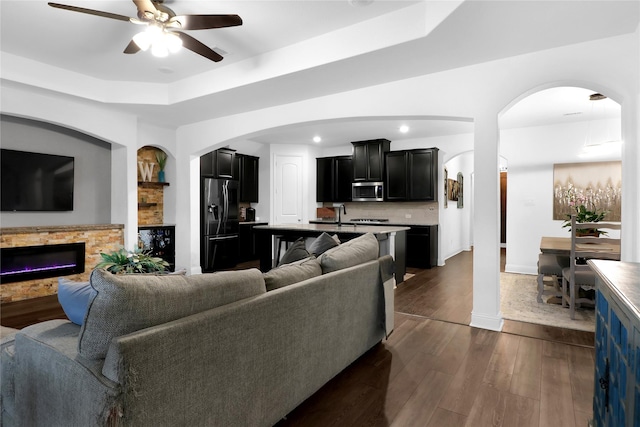 14649 Martin Creek Cv, Fort Worth, TX 76262 - living room with a ceiling fan, arched walkways, a tray ceiling, a glass covered fireplace, and recessed lighting