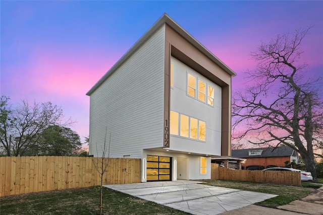 1902 Homeland St, Dallas, TX 75212 - property exterior at dusk featuring fence, a patio area, and stucco siding
