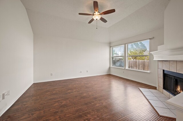 8329 Rolling Rock Dr, Fort Worth, TX 76123 - unfurnished living room featuring ceiling fan, a tiled fireplace, vaulted ceiling, wood finished floors, and baseboards