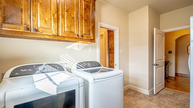 169 Star Point Ln, Weatherford, TX 76088 - laundry area featuring arched walkways, washer and clothes dryer, cabinet space, and baseboards