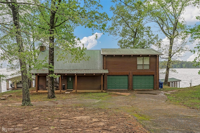 cabin with log siding, metal roof, and driveway