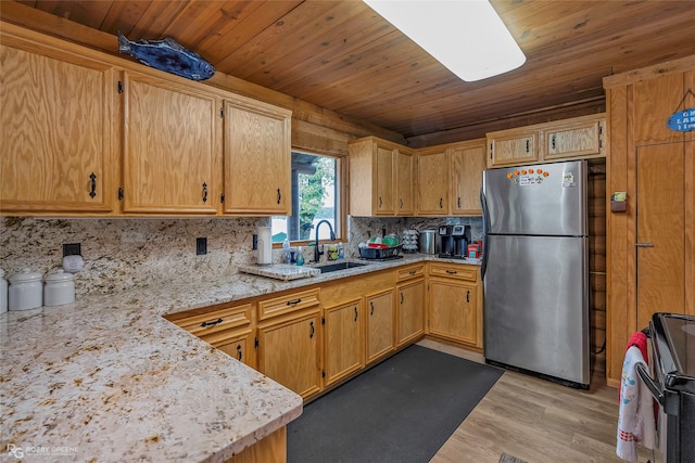 kitchen featuring light wood-style flooring, electric range, freestanding refrigerator, backsplash, and a sink