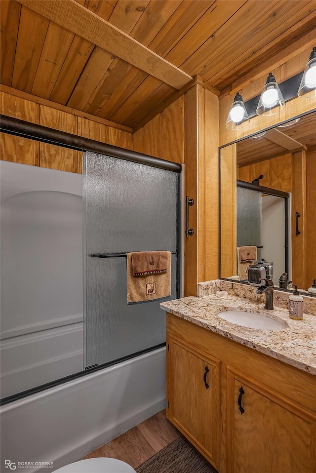 bathroom featuring wooden ceiling, combined bath / shower with glass door, wooden walls, vanity, and wood finished floors