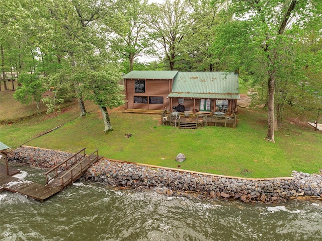 rear view of house with a yard, metal roof, a deck with water view, and log veneer siding