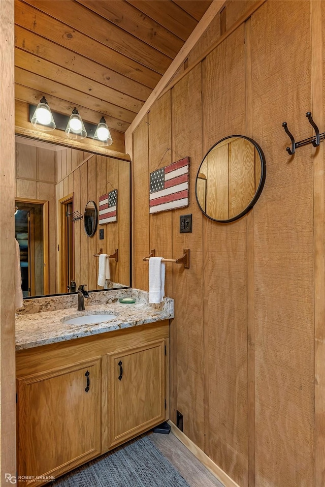 bathroom with wood ceiling, wooden walls, and vanity