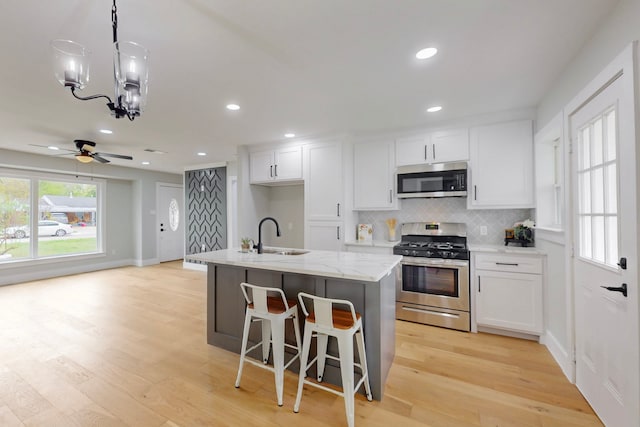 10503 Cayuga Dr, Dallas, TX 75228 - kitchen featuring stainless steel appliances, a sink, white cabinets, tasteful backsplash, and light wood-style floors