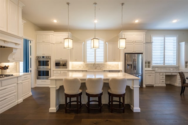 2813 Maverick Way, Celina, TX 75009 - kitchen featuring appliances with stainless steel finishes, a sink, backsplash, a center island, and white cabinetry
