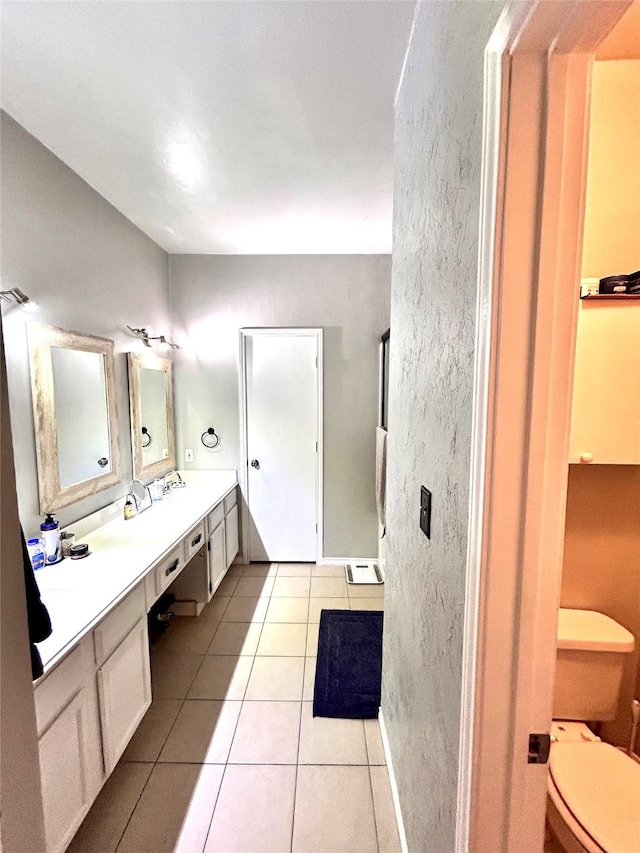 bathroom featuring a sink, double vanity, toilet, and tile patterned floors