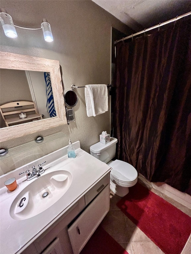 full bathroom featuring a shower with curtain, tile patterned flooring, vanity, toilet, and a textured wall