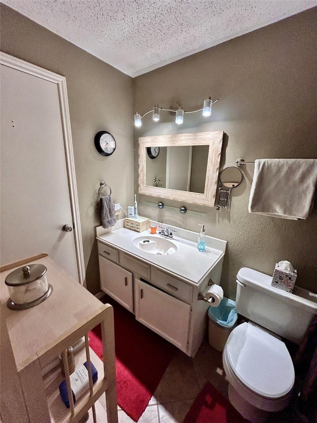 bathroom with toilet, vanity, tile patterned floors, and a textured ceiling