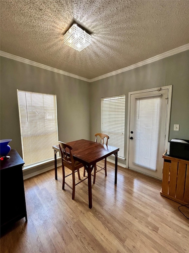 dining room featuring light wood-style flooring, ornamental molding, and a textured ceiling
