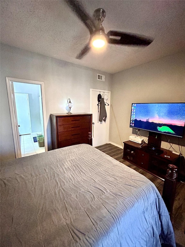 bedroom featuring a ceiling fan, wood finished floors, a textured ceiling, and visible vents