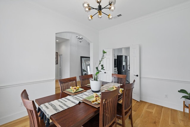 809 Chiswick Ct, Haslet, TX 76052 - dining area with a chandelier, arched walkways, crown molding, light wood-style floors, and baseboards