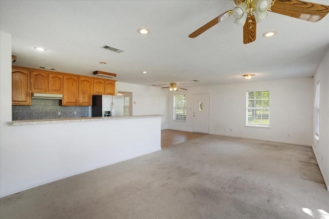 kitchen with ceiling fan, light countertops, light colored carpet, stainless steel refrigerator with ice dispenser, and under cabinet range hood