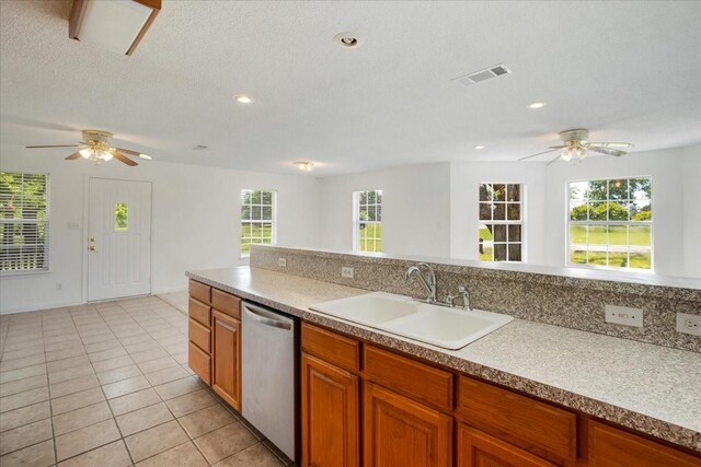kitchen featuring brown cabinets, stainless steel dishwasher, a ceiling fan, and a sink