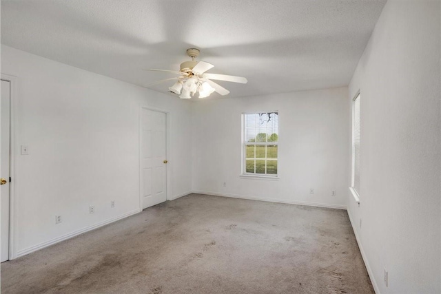 carpeted spare room with ceiling fan and baseboards