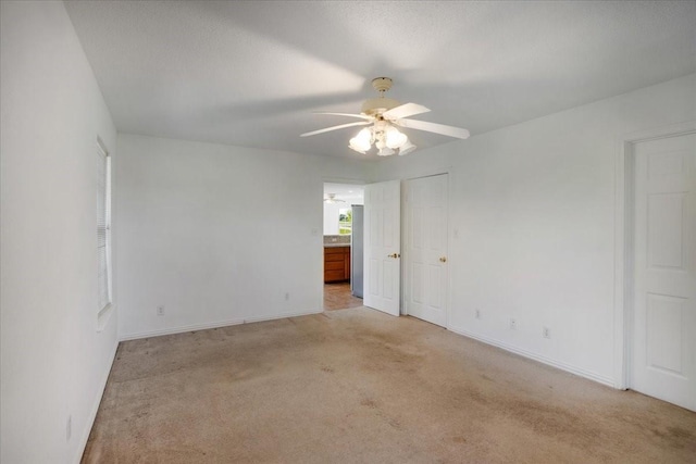 unfurnished room with light carpet, a ceiling fan, and baseboards