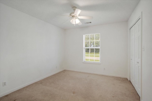 unfurnished bedroom with a closet, baseboards, light carpet, and visible vents