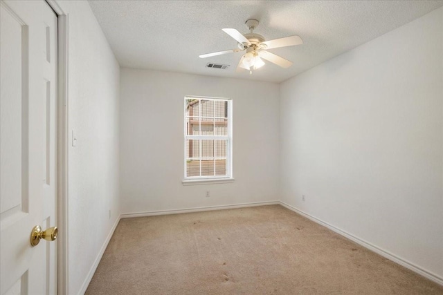 carpeted empty room with a textured ceiling, visible vents, a ceiling fan, and baseboards