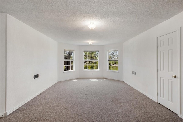 carpeted empty room featuring baseboards, visible vents, and a textured ceiling