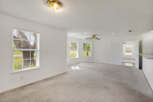 unfurnished living room with carpet floors, a textured ceiling, ceiling fan, and a healthy amount of sunlight