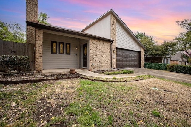 mid-century home featuring an attached garage, fence, brick siding, and concrete driveway
