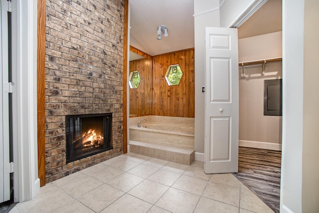 bathroom with tile patterned floors, wooden walls, a bath, electric panel, and a fireplace