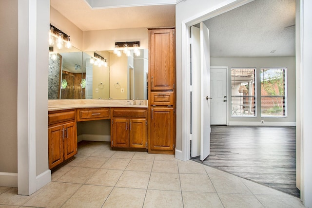 bathroom featuring a textured ceiling, baseboards, a notable chandelier, tile patterned flooring, and vanity