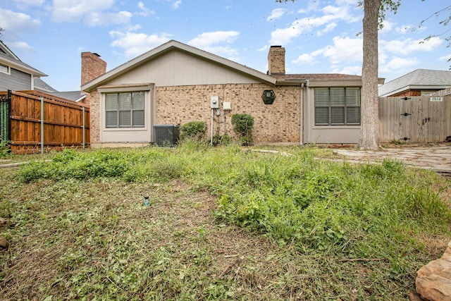 back of property with fence, a chimney, and brick siding