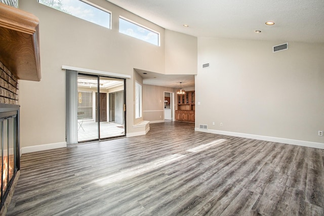 unfurnished living room with plenty of natural light, wood finished floors, visible vents, and a chandelier