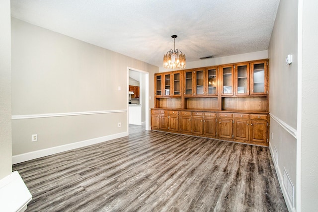 interior space featuring dark wood finished floors, visible vents, baseboards, and an inviting chandelier