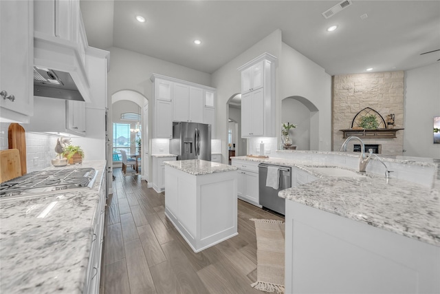 kitchen with arched walkways, visible vents, appliances with stainless steel finishes, and a sink
