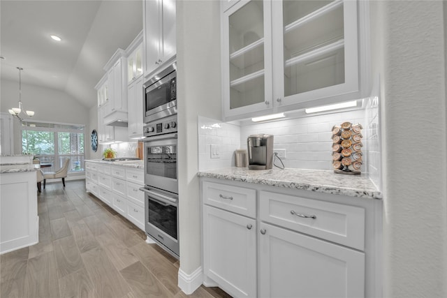 kitchen with lofted ceiling, stainless steel appliances, light wood-type flooring, glass insert cabinets, and white cabinetry