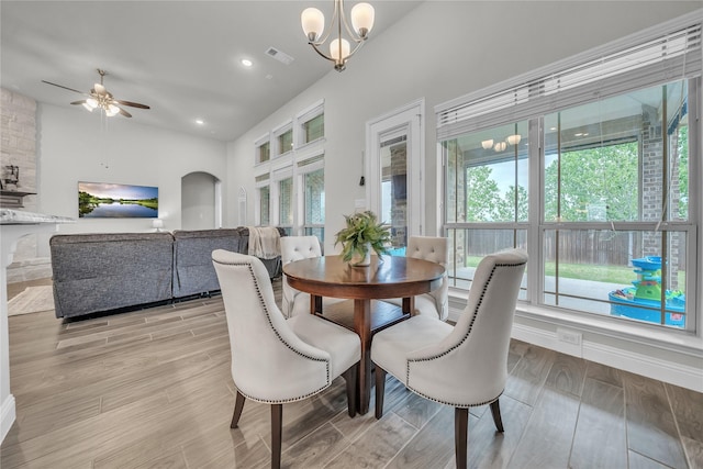 dining area with light wood finished floors, arched walkways, visible vents, recessed lighting, and ceiling fan with notable chandelier