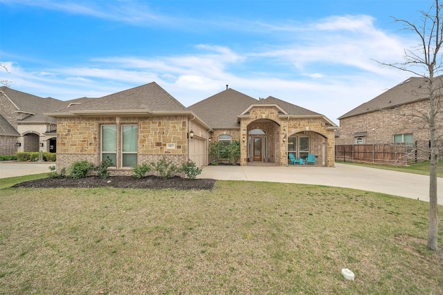 french country home with brick siding, driveway, a front lawn, and fence