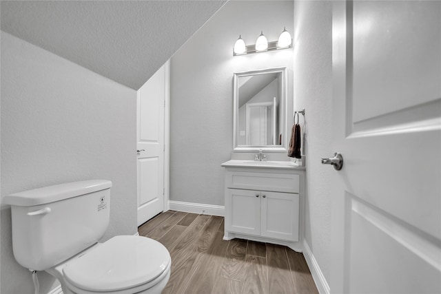 bathroom featuring lofted ceiling, toilet, vanity, and wood finished floors