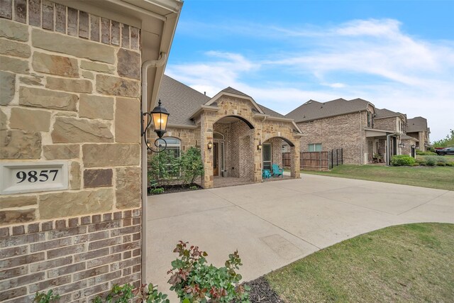 french country inspired facade featuring fence, brick siding, a front yard, and roof with shingles